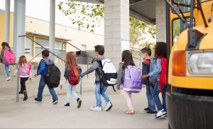 Young students exiting a bus and walking in to school